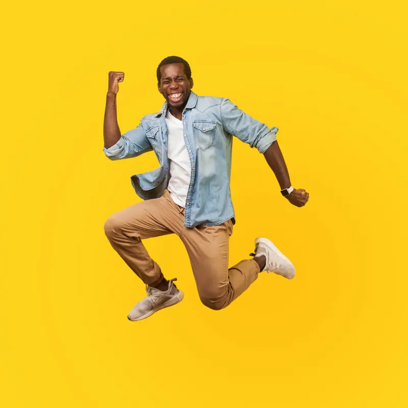 A man jumping for joy against a yellow wall
