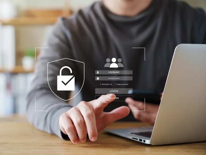 A person signing in on a laptop, with a padlock and shield drawn over the screen